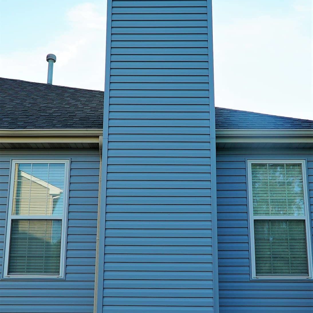 A blue chimney between two windows.