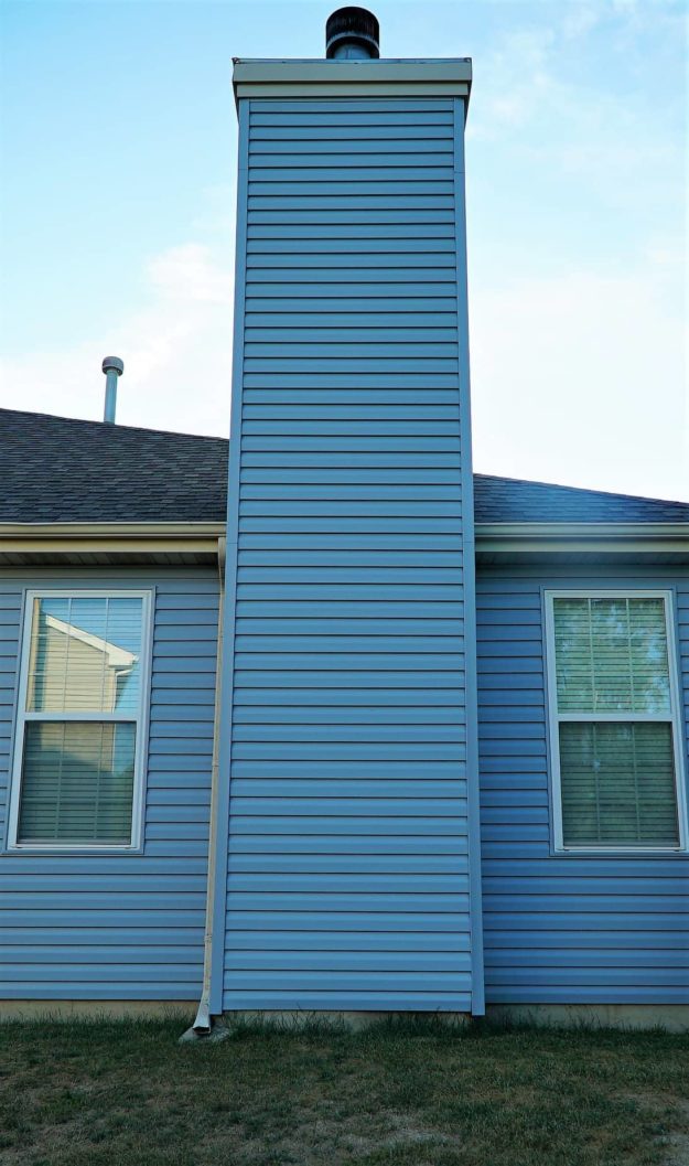 A blue chimney between two windows.