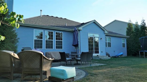 This backyard contains a trampoline, lounge chairs and a table.