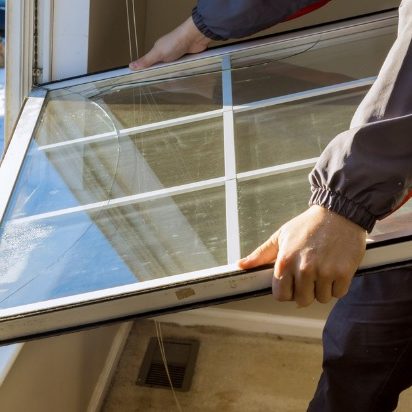 Worker taking an old window out of the frame to replace with a new one.
