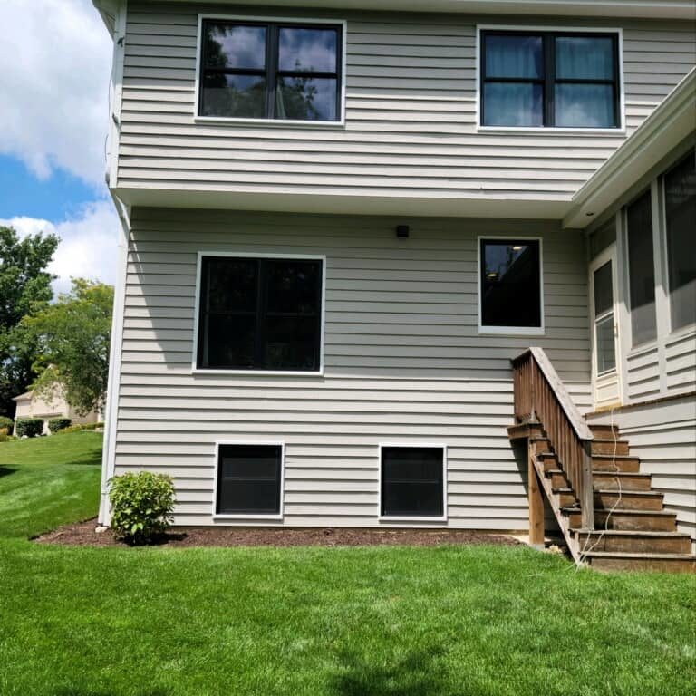 Black frames contrast against a tan house.