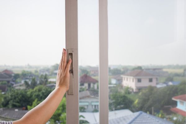 Woman’s hand opening a sliding glass window
