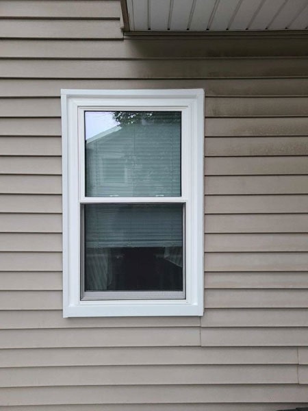 A white double hung window's shades are partially ajar.