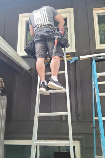 One of our expert installers uses a ladder to reach a window.