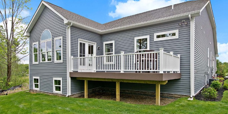 The exterior of the back of a house with blue siding and a wooden deck.