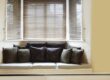 A bay window with blinds in a kitchen with couch area