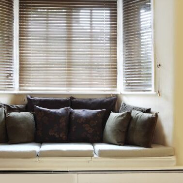 A bay window with blinds in a kitchen with couch area