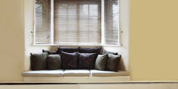 A bay window with blinds in a kitchen with couch area